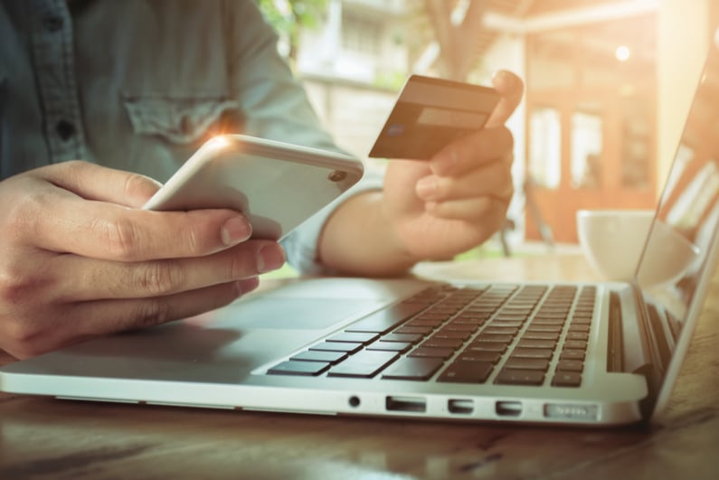 Man's hands holding smartphone and using credit card