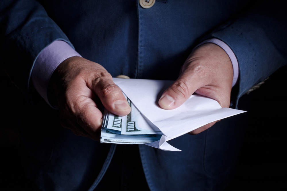 a pair of hands holding an envelope containing dollars