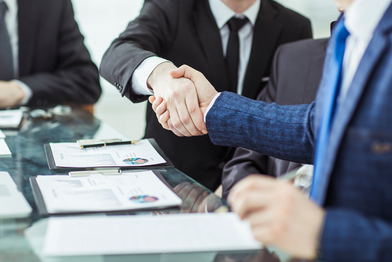 Two men dressed in suits shaking hands on a financial agreement.