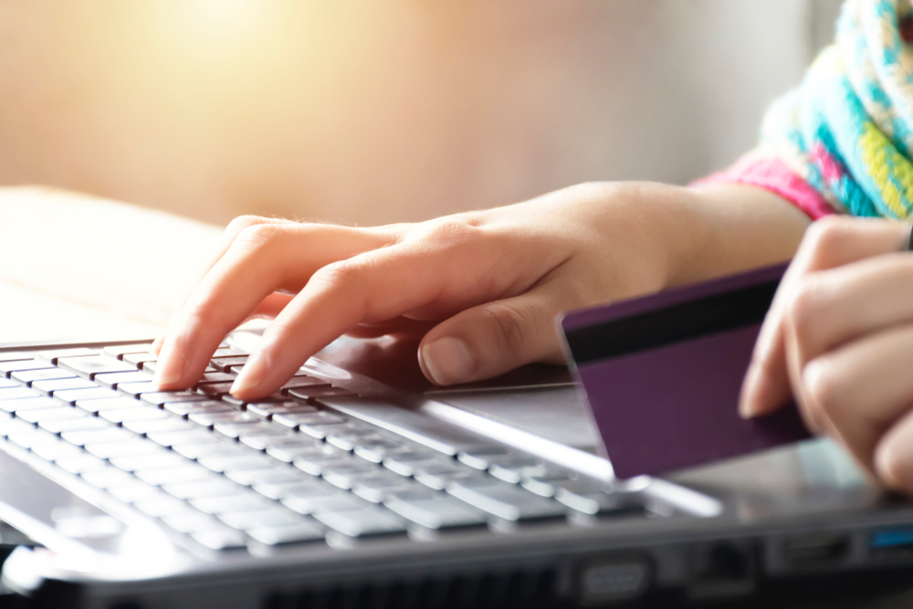 female's hand holding credit card while on laptop