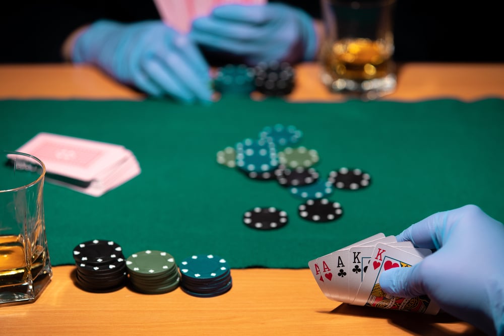 Two people play poker wearing surgical gloves