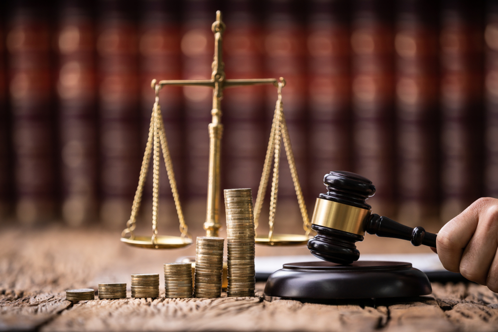 A judge's gavel with scales and ascending piles of coins