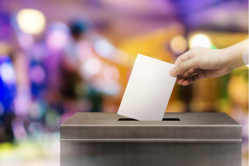 Person putting a vote into a ballot box